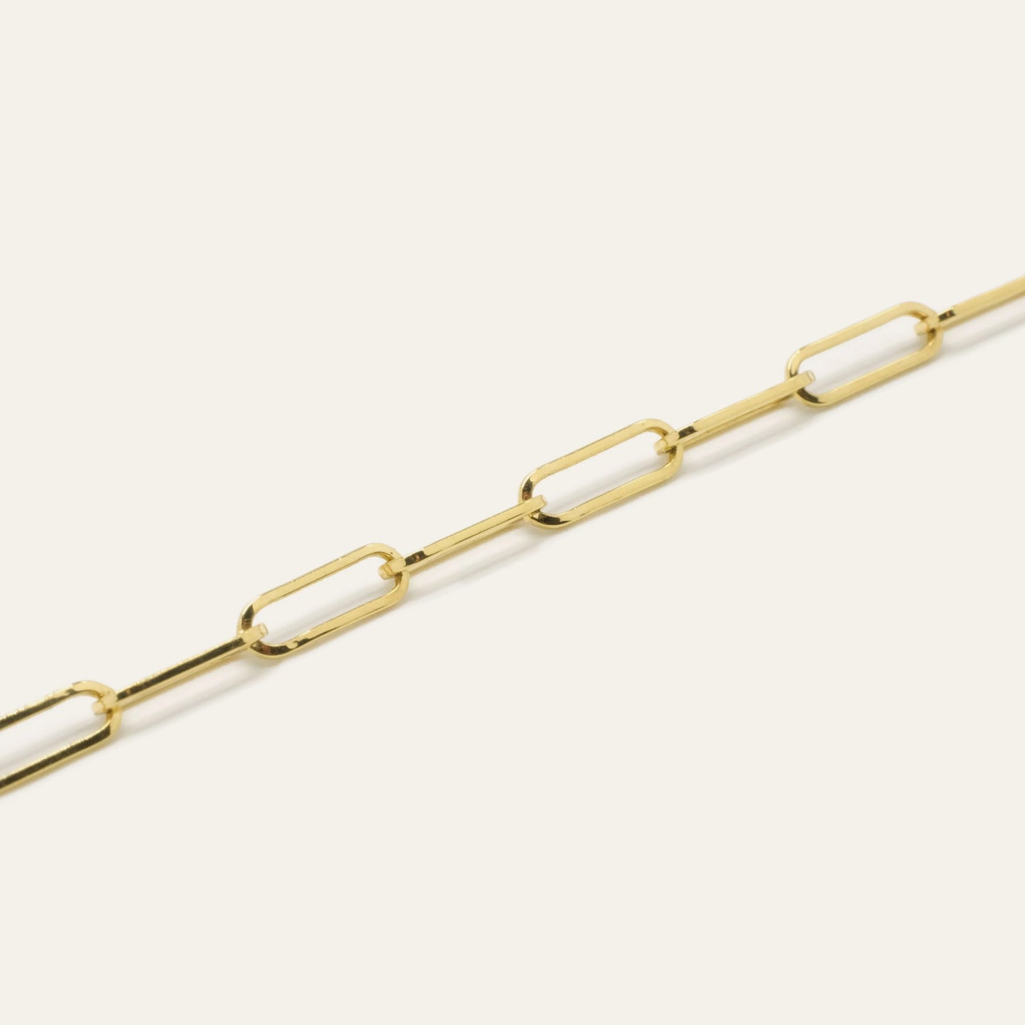 Gold chain bracelet on a light beige background