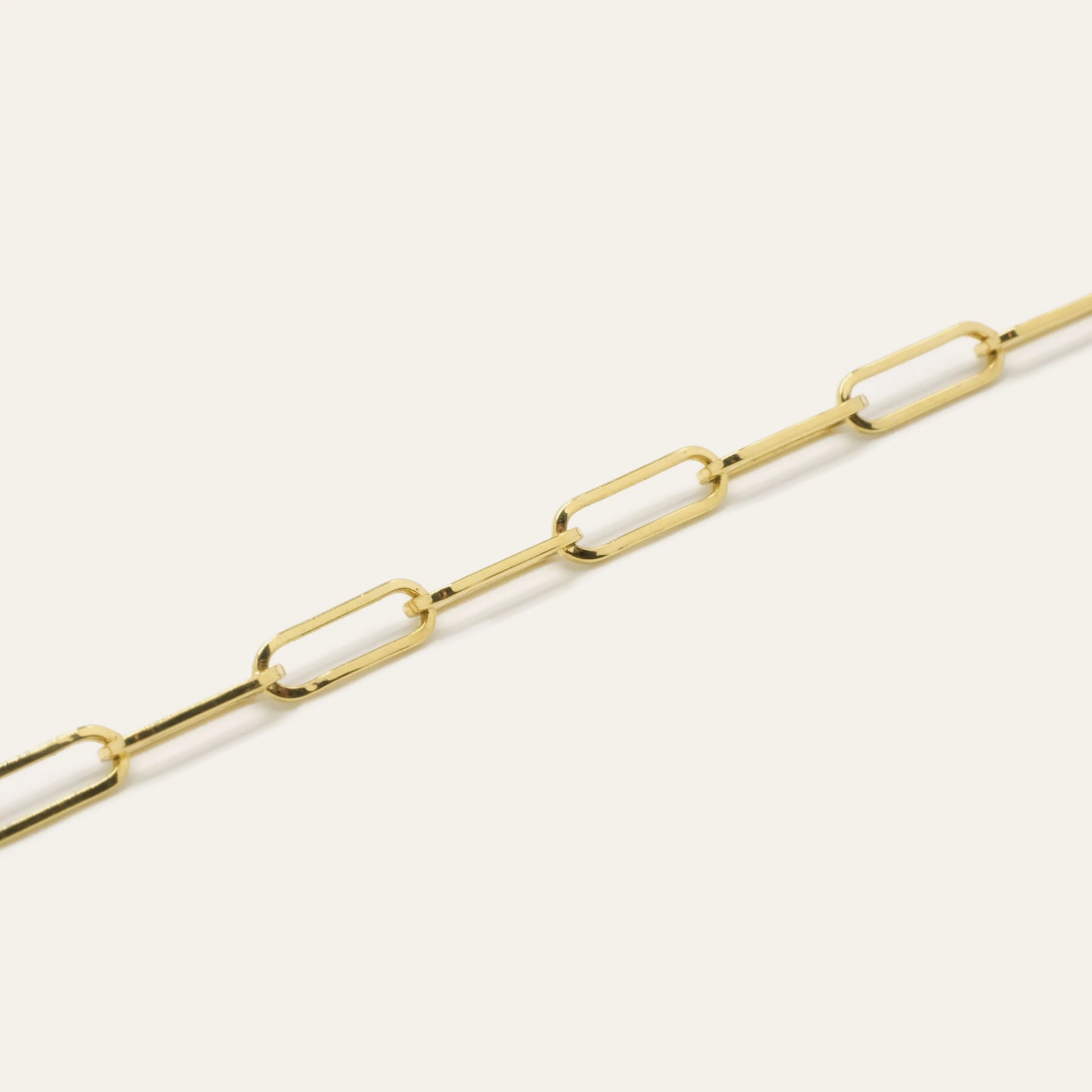 Gold chain bracelet on a light beige background