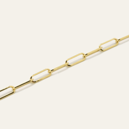 Gold chain bracelet on a light beige background