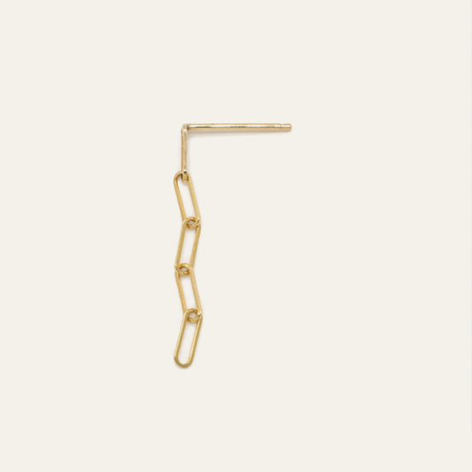 Gold chain earring on a light beige background