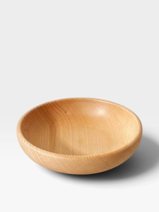 Shallow beech wood bowl sitting on a light gray background