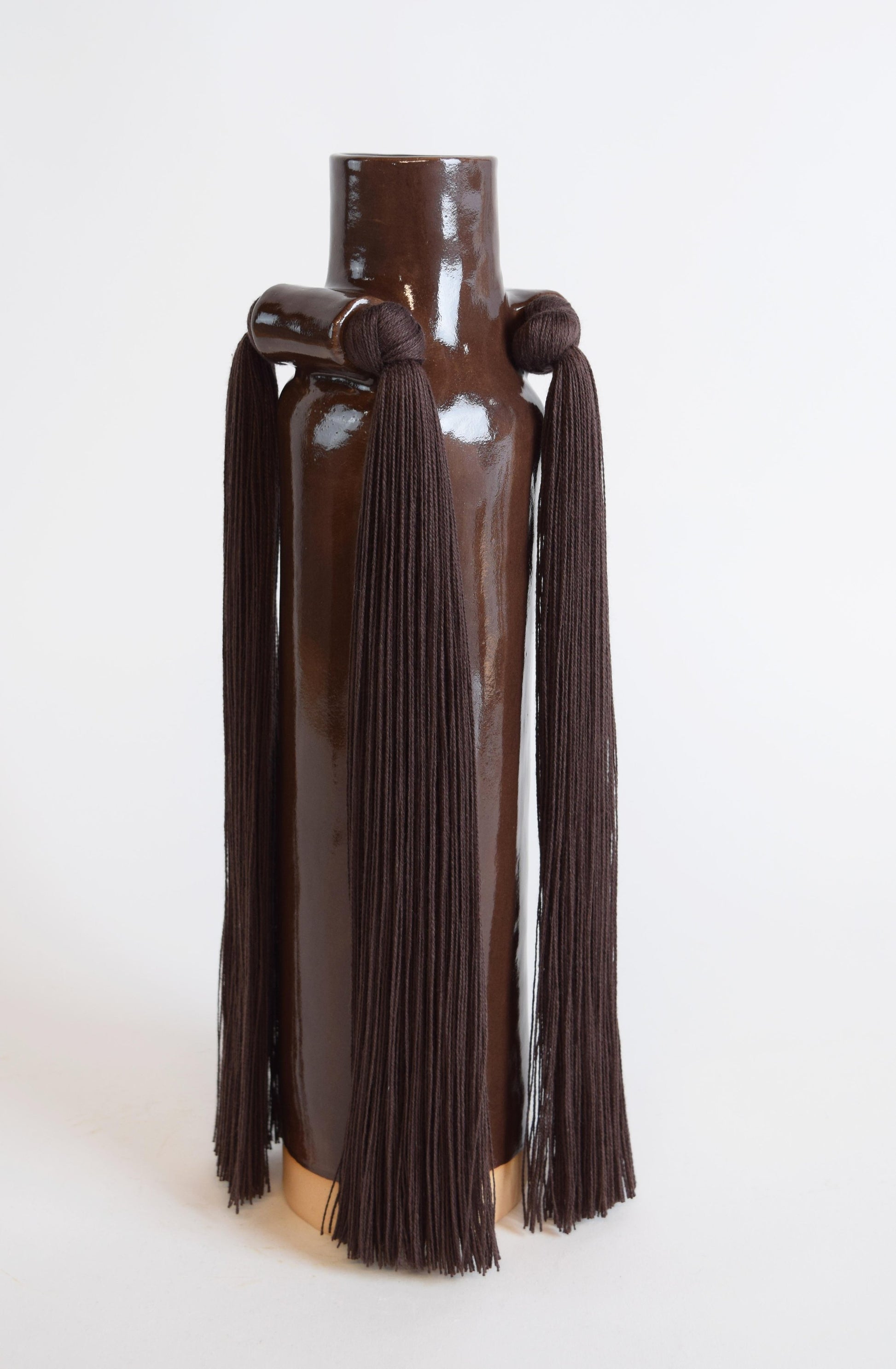 A brown stoneware vase with a fringe detail in a braided design, displayed against a plain background.