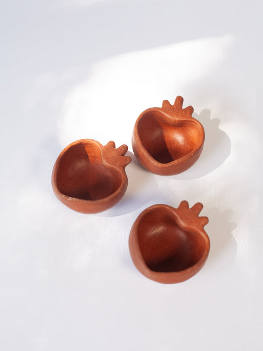 Three petite, heart-shaped red clay dishes on a white background, crafted in Oaxaca, Mexico.
