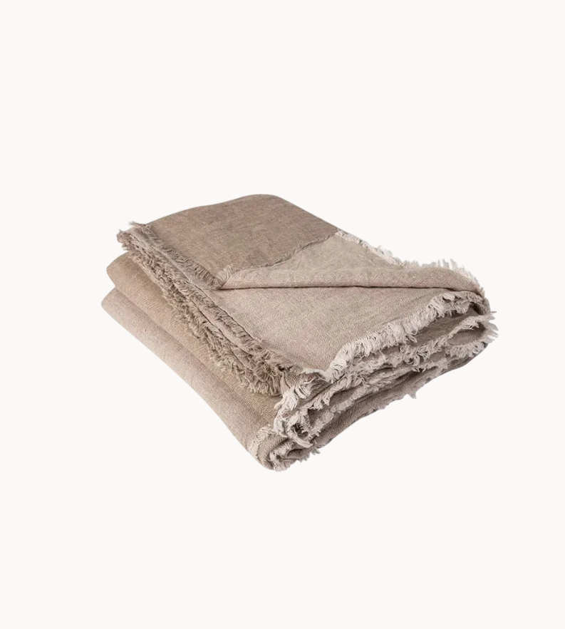 Beige throw blanket with frayed edges on a white background