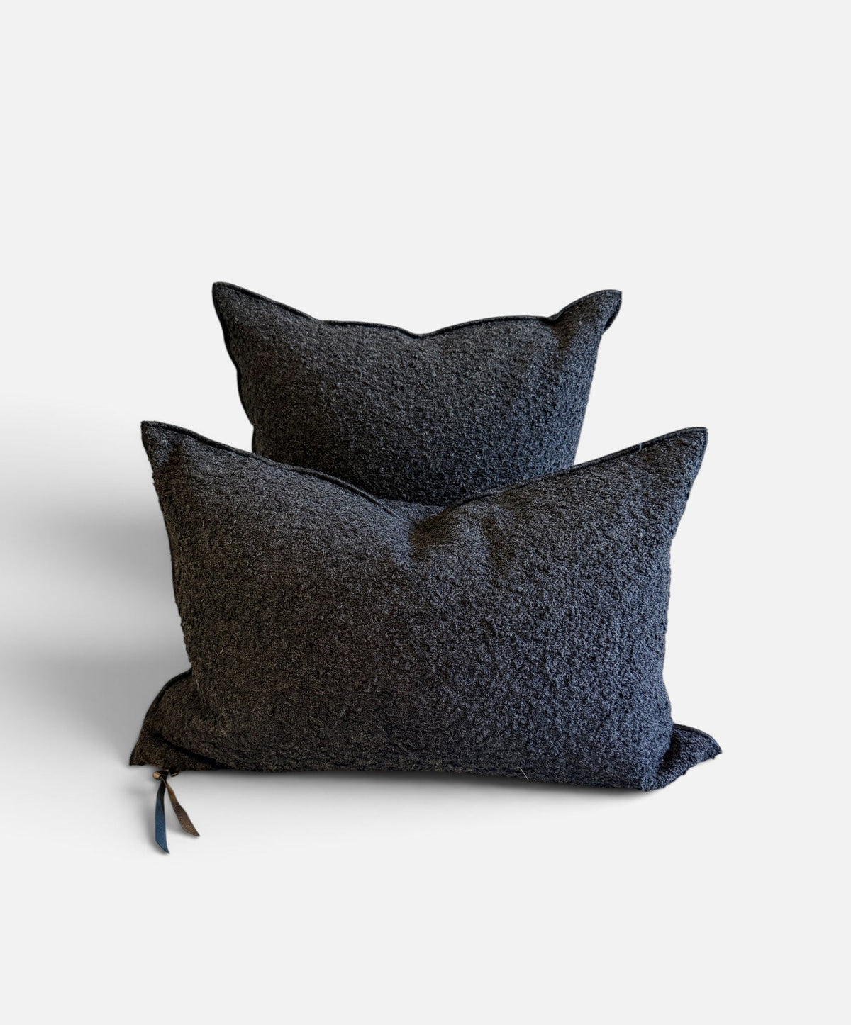 Two dark charcoal textured throw pillows stacked on a light gray background.