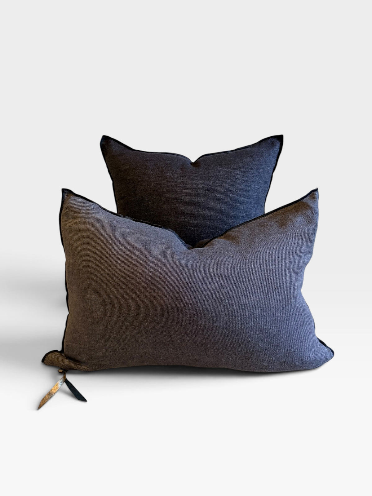 Two textured throw pillows in dark charcoal gray and black, arranged with one in front of the other on a clean white background.
