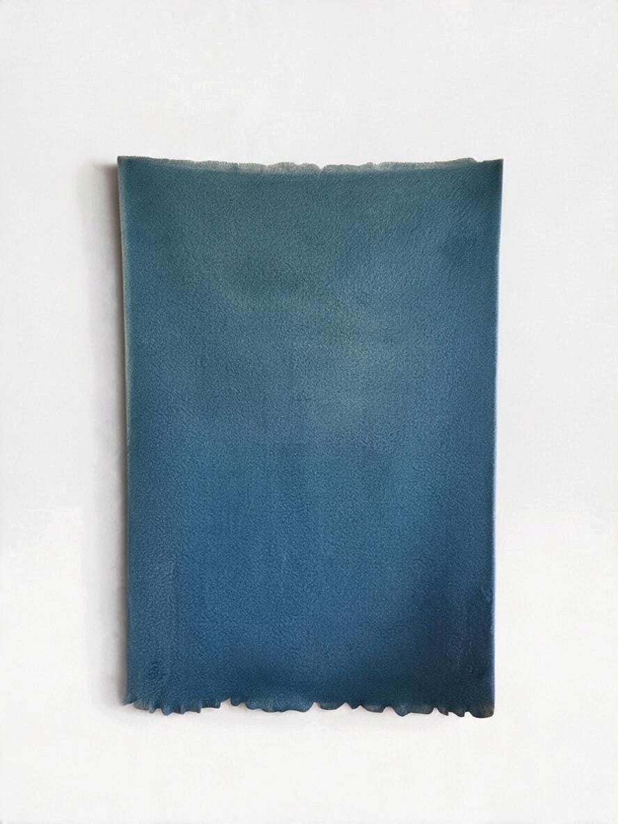 Dark teal colored mohair blanket laid flat on a white background
