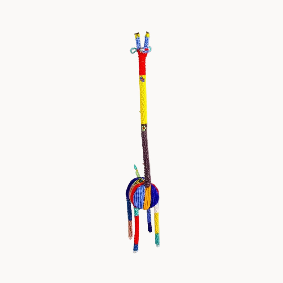 A handmade beaded giraffe toy or decorative figure, featuring a long neck and legs with colorful beads in red, yellow, blue, brown, and white, set against a plain white background.