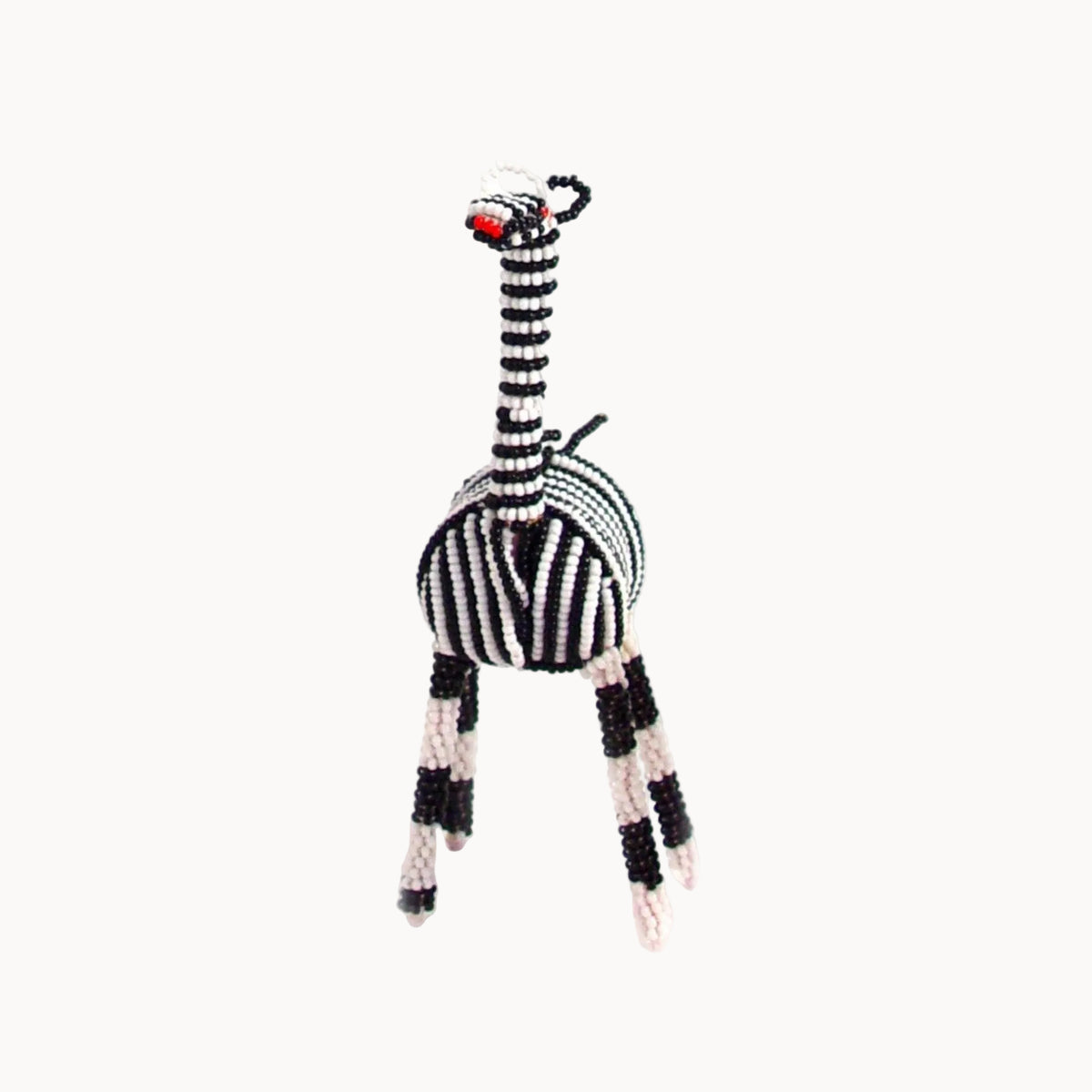 A handmade beaded zebra figurine with a long striped neck, striped body, and striped legs, featuring a small red beaded nose, set against a plain white background.
