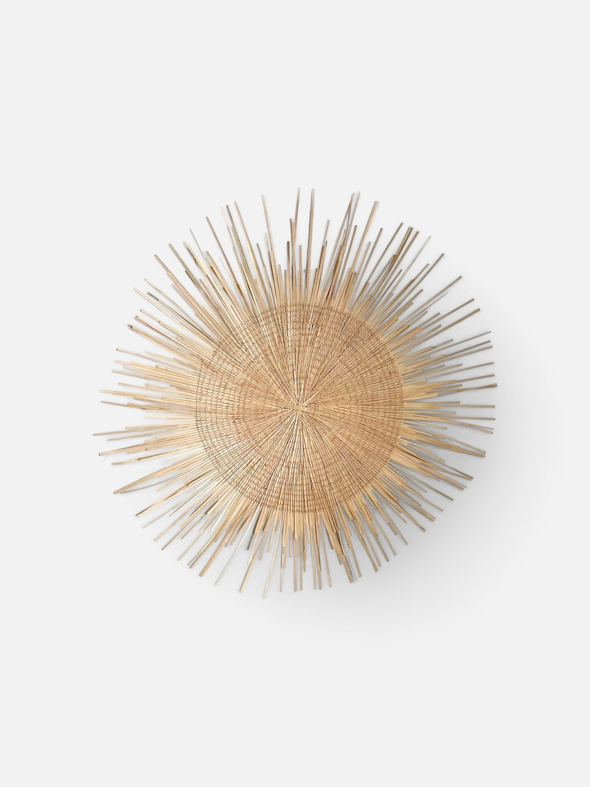 A circular woven sunburst wall sculpture made of natural light brown wood rods radiating from a round central base, shown against a plain light gray background.