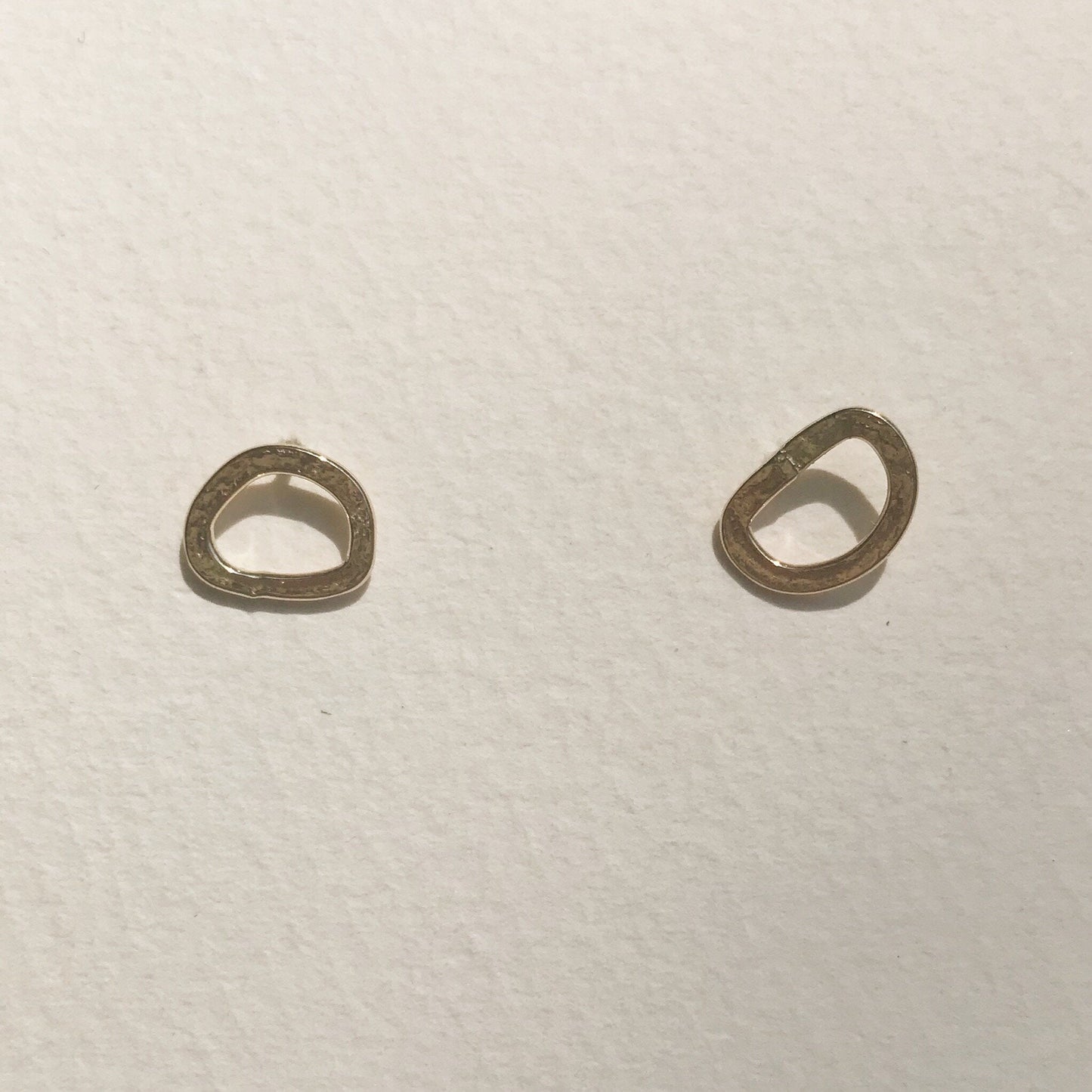 A pair of small gold hoop earrings placed against a white background.
