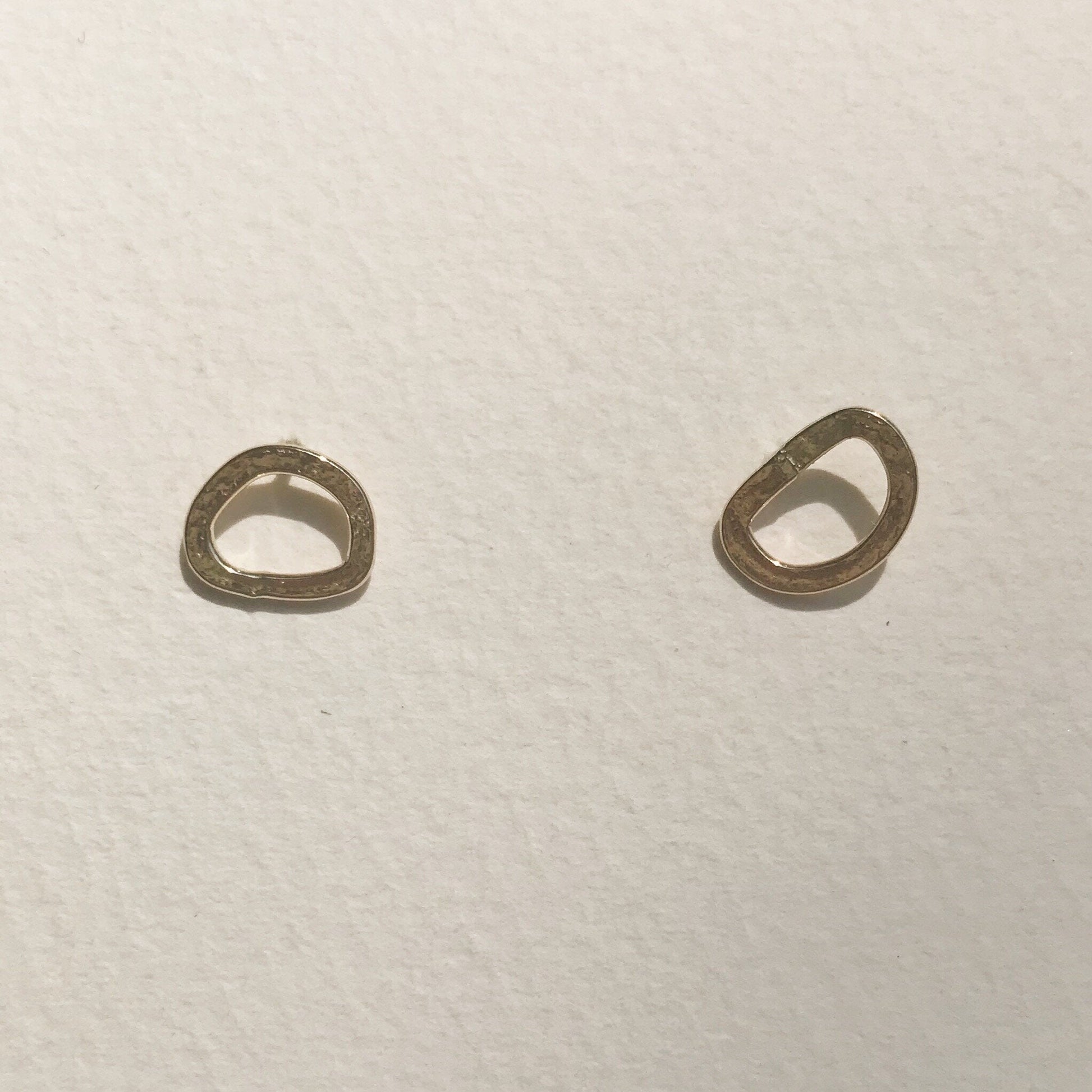 A pair of small gold hoop earrings placed against a white background.