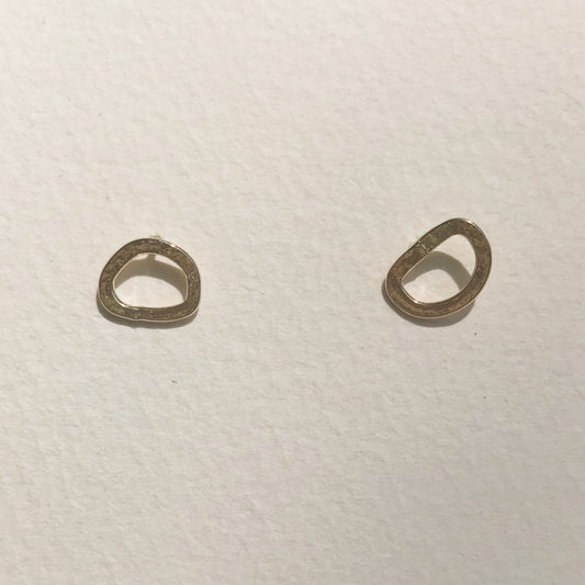 A pair of small gold hoop earrings placed against a white background.