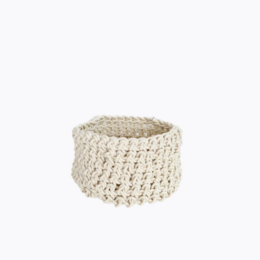 A beige cotton rope basket made by hand, with a textured weave pattern.