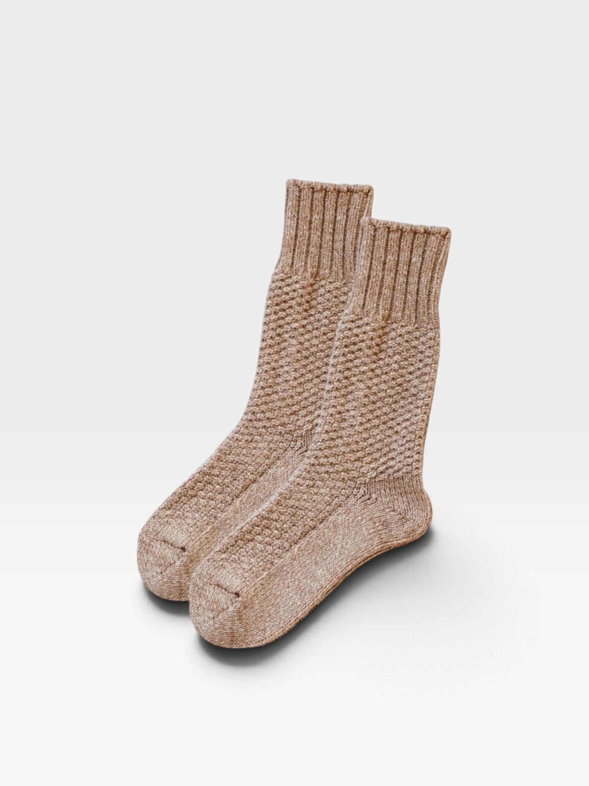 Pair of beige-colored wool and cotton socks with a basket-style weave pattern photographed on a white background