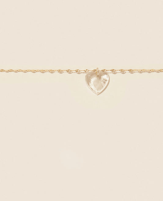 A gold necklace with a heart-shaped carved pendant hanging from a diamond pave bale, on a plain background.
