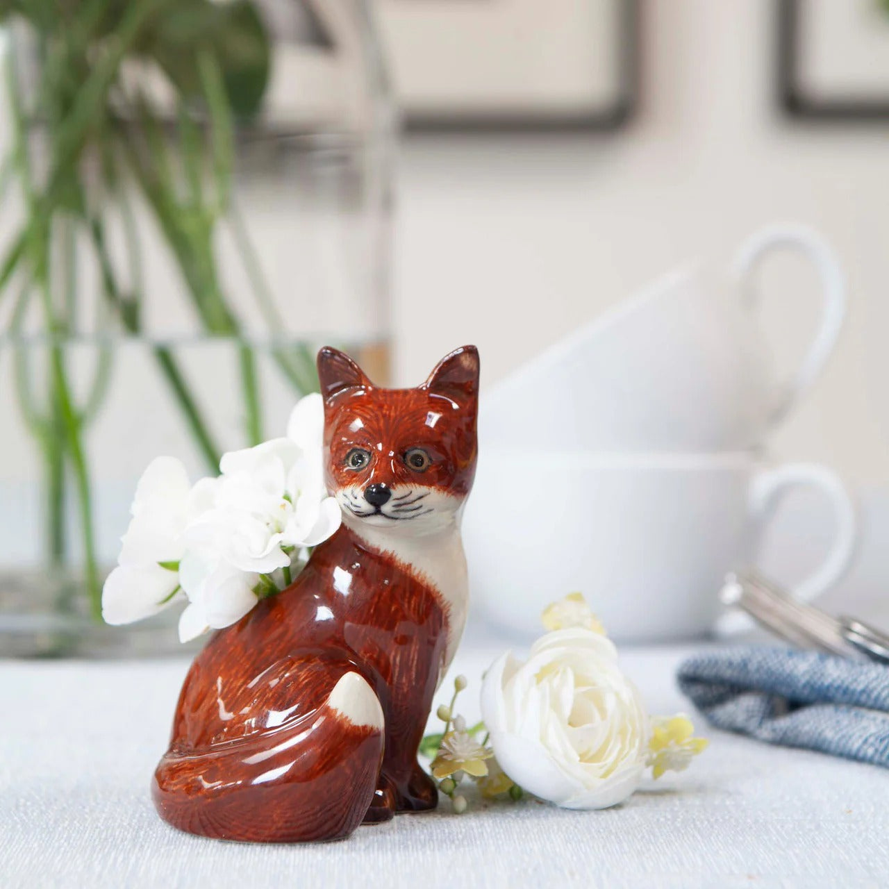 Ceramic fox vase with white flowers on a table