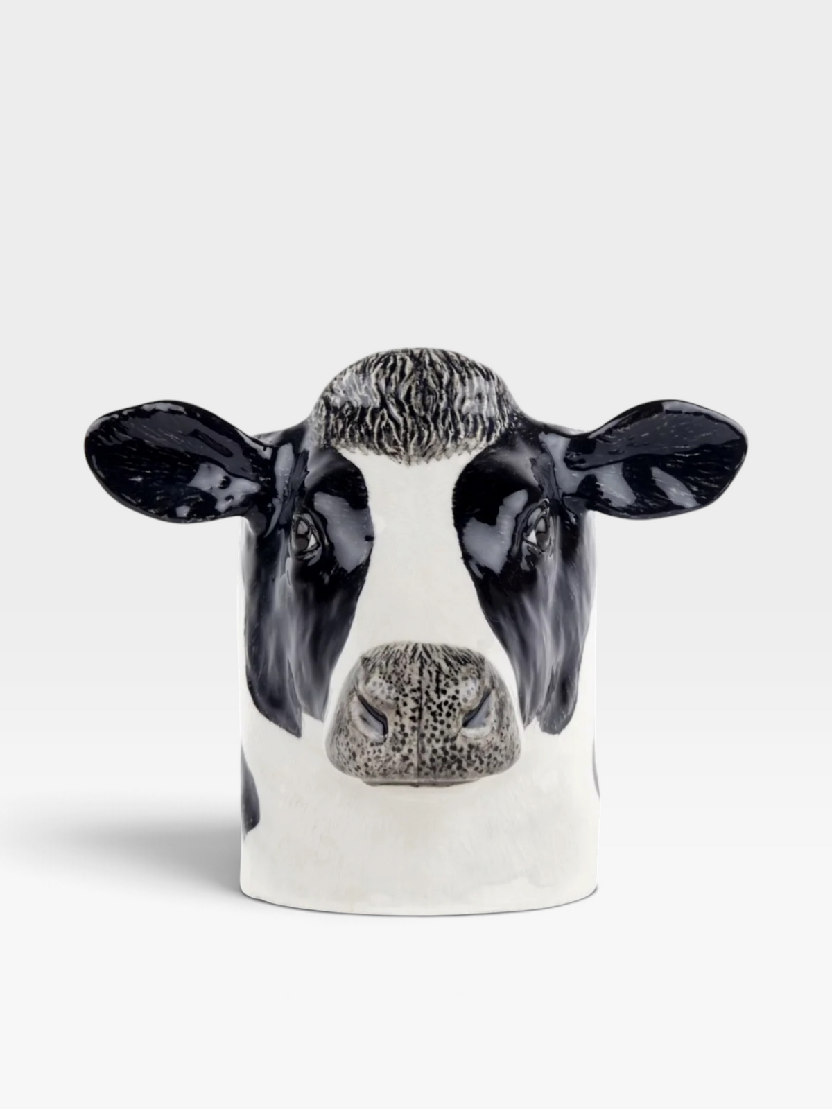Ceramic cow pencil pot with black and white markings set against a white background