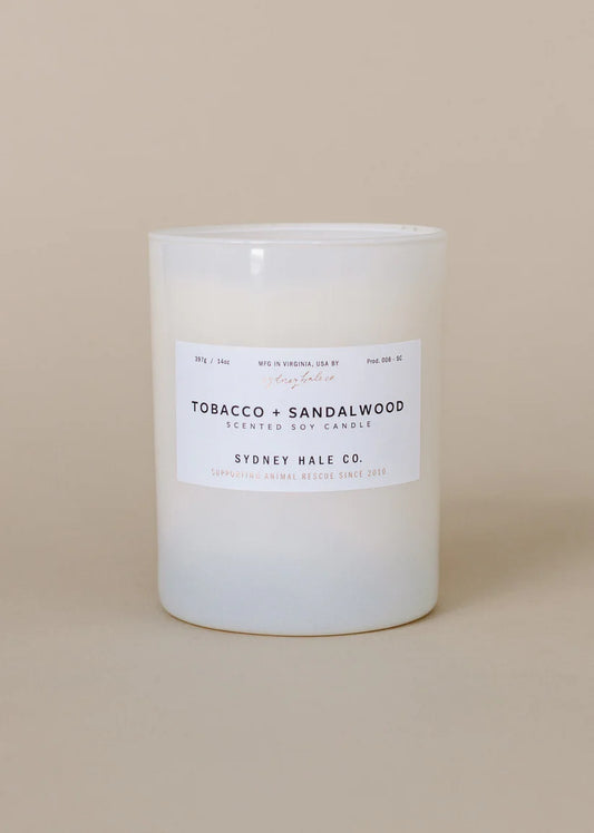 Tobacco and sandalwood candle with a white label on a beige background