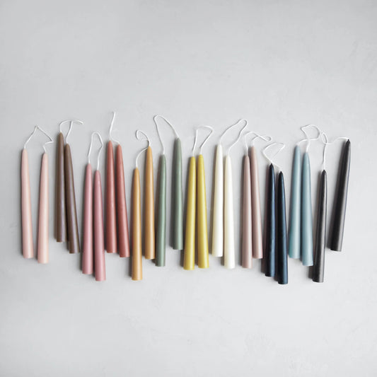 Set of colorful taper candles arranged in a row on a light gray background
