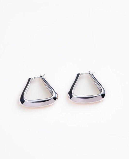 Triangle shaped silver hoop earrings on a pale gray background