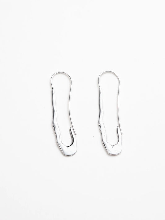 Pair of silver earrings with a safety pin-like shape on a white background