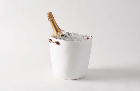 White, organic, smooth form champagne bucket with leather handles against a plain backround