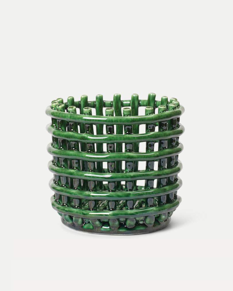 A green ceramic woven planter set against a soft white background