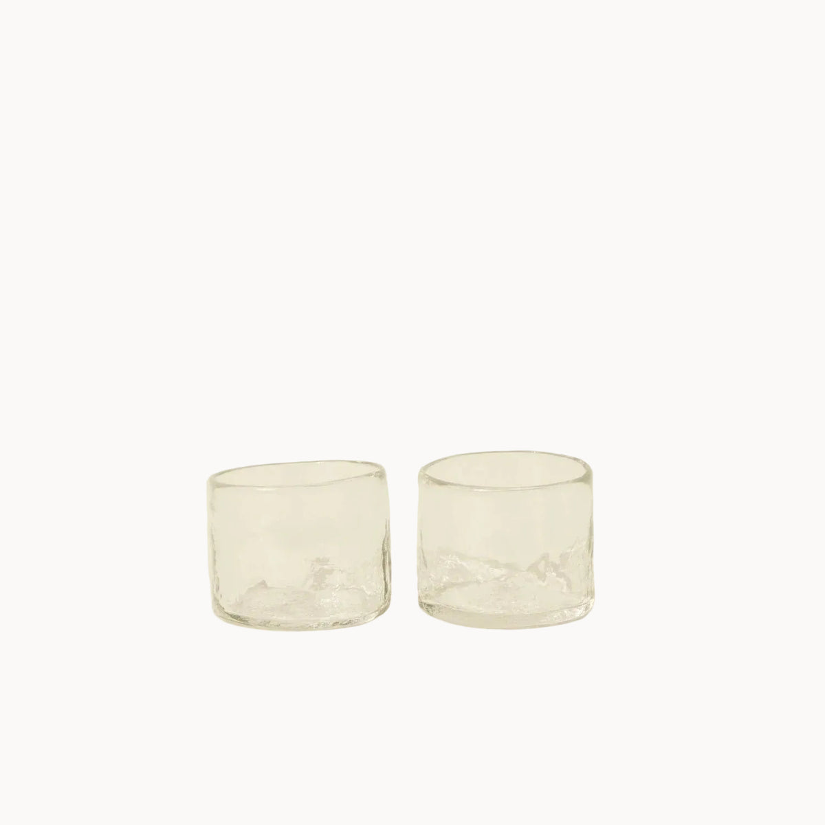 Two clear glass tumblers on a beige background