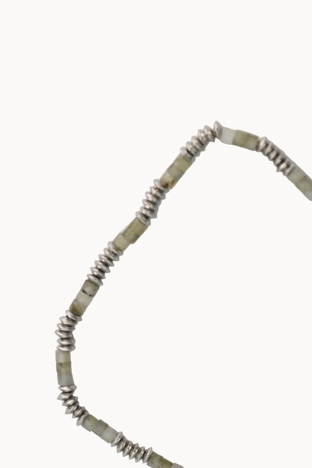 Necklace with green beads and silver chain on a light gray background
