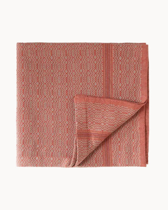 Red patterned cloth napkin folded with one corner turned up and set on a white background