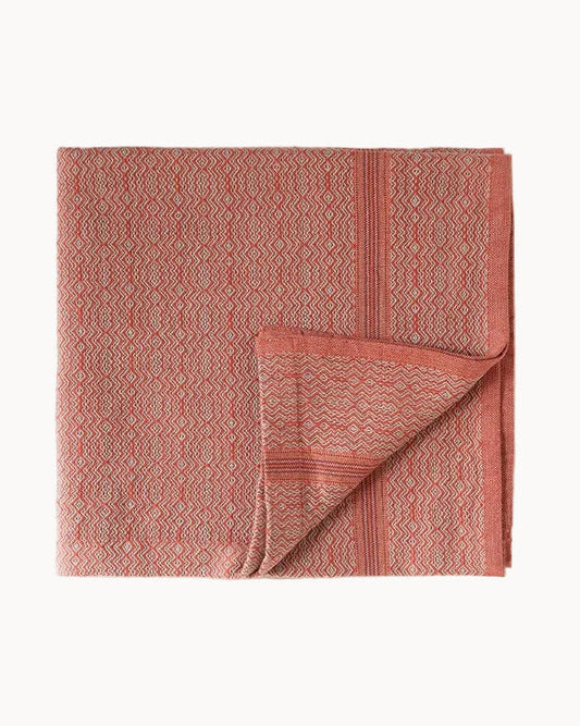Red patterned cloth napkin folded with one corner turned up and set on a white background