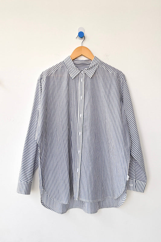 Blue and white striped women's button-down shirt on a hanger against a white background