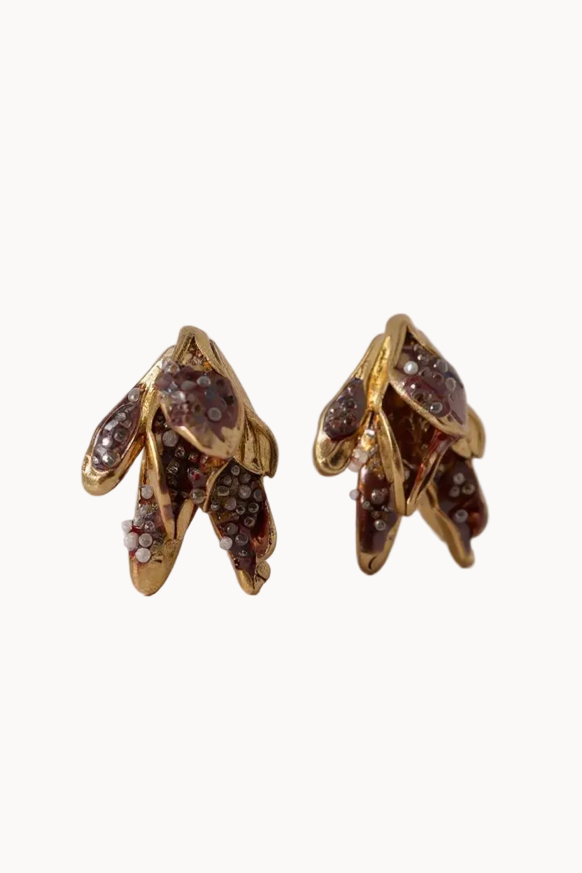 Gold earrings with brown glass detailing on a light gray background