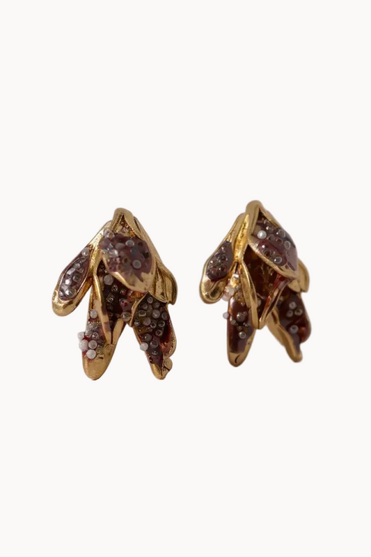 Gold earrings with brown glass detailing on a light gray background