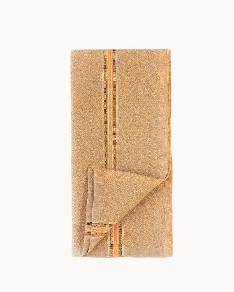 A folded golden-hued woven cloth napkin with vertical orange and yellow stripes, displayed on a clean white background.
