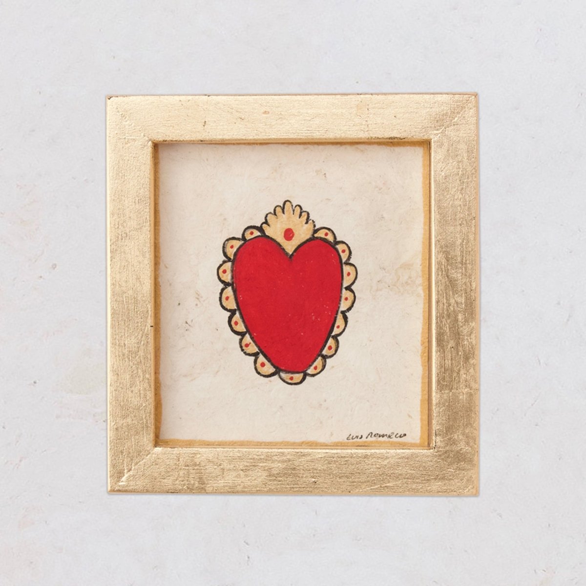 A framed painting of a red heart with a golden-leaf wooden frame and a mat, inspired by traditional milagros.