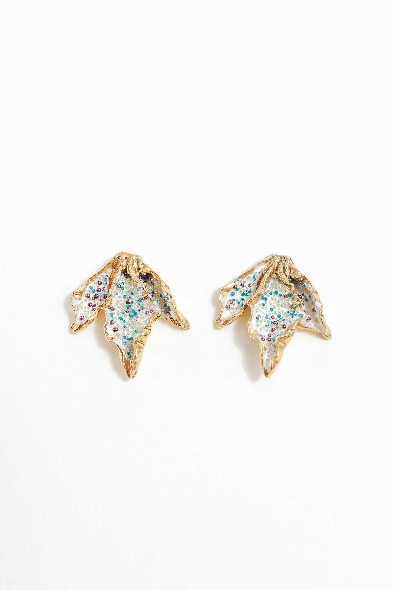 Gold and beaded leaf-shaped earrings on a white background