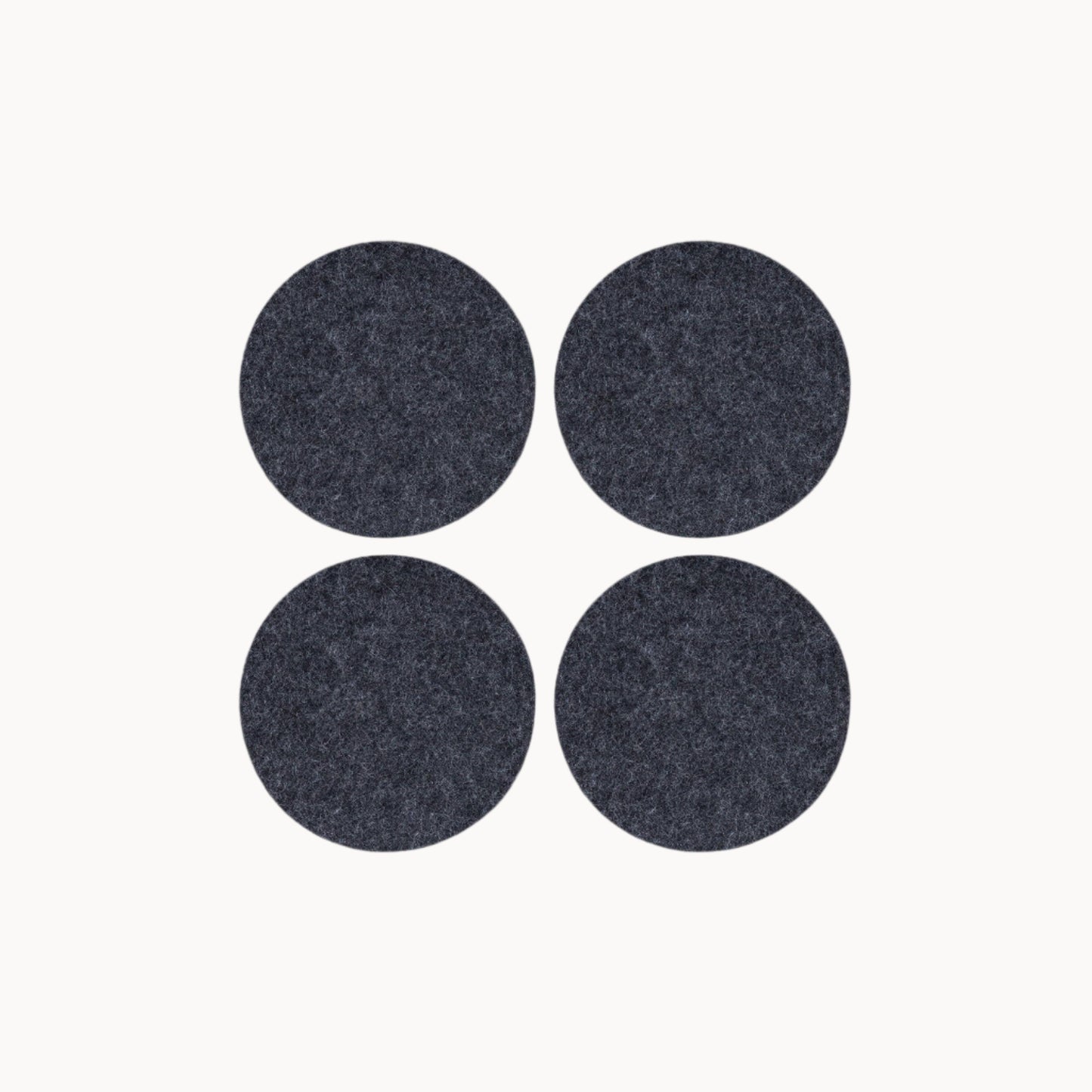 Four dark gray round wool felt coasters on a white background