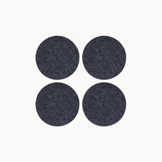 Four dark gray round wool felt coasters on a white background