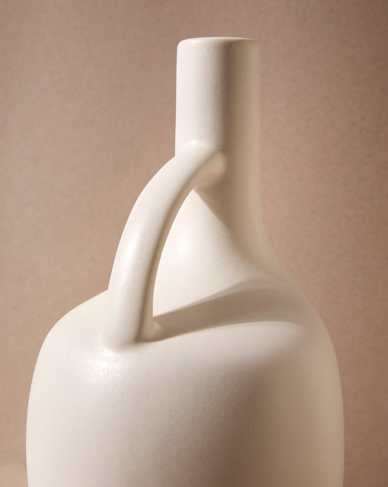 A close up of the upper portion of a white ceramic olive oil dispenser with a handle