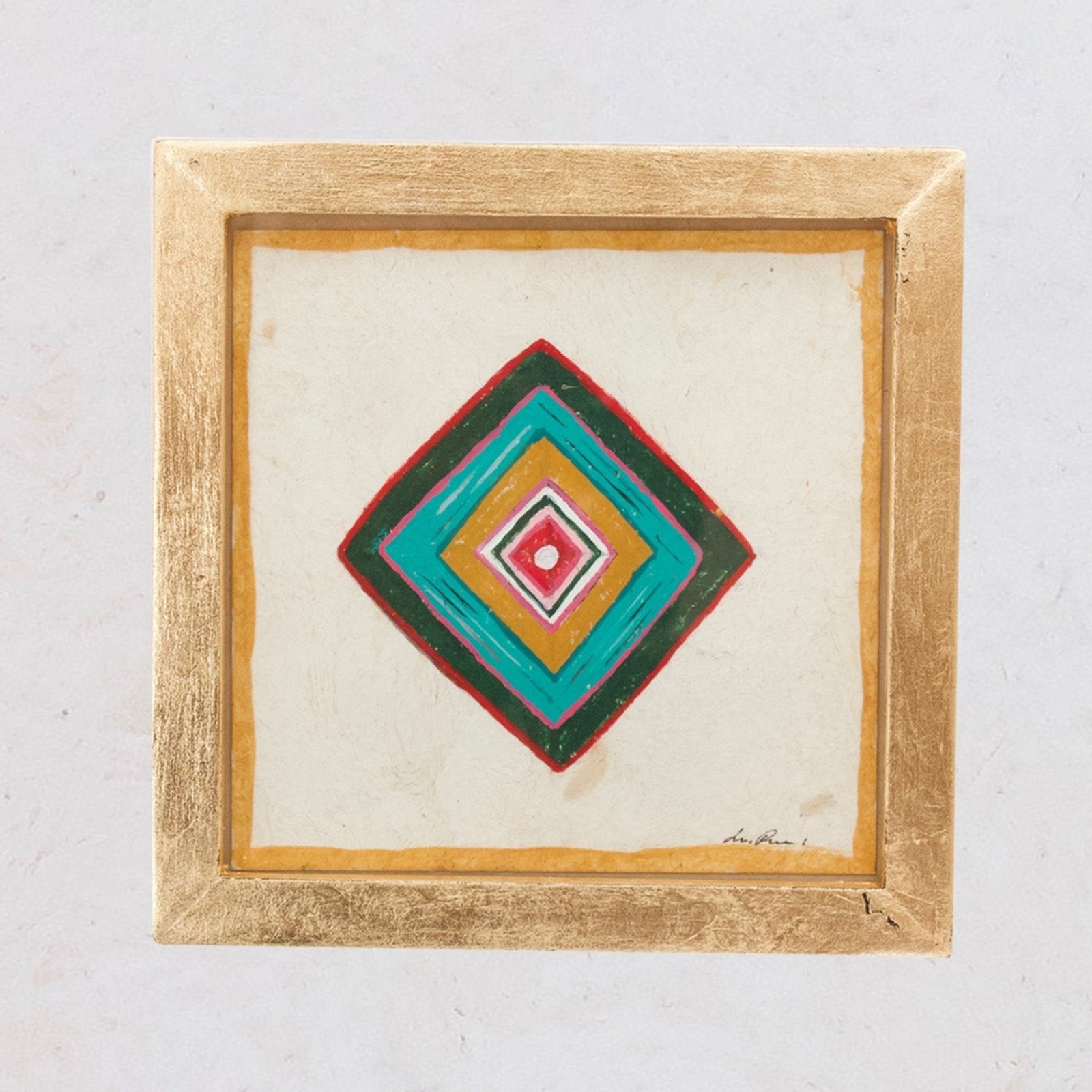 A framed painting of the Ojo de Dios symbol, featuring concentric diamond shapes with a red, blue, and green on a beige background, signed by Luis Romero.