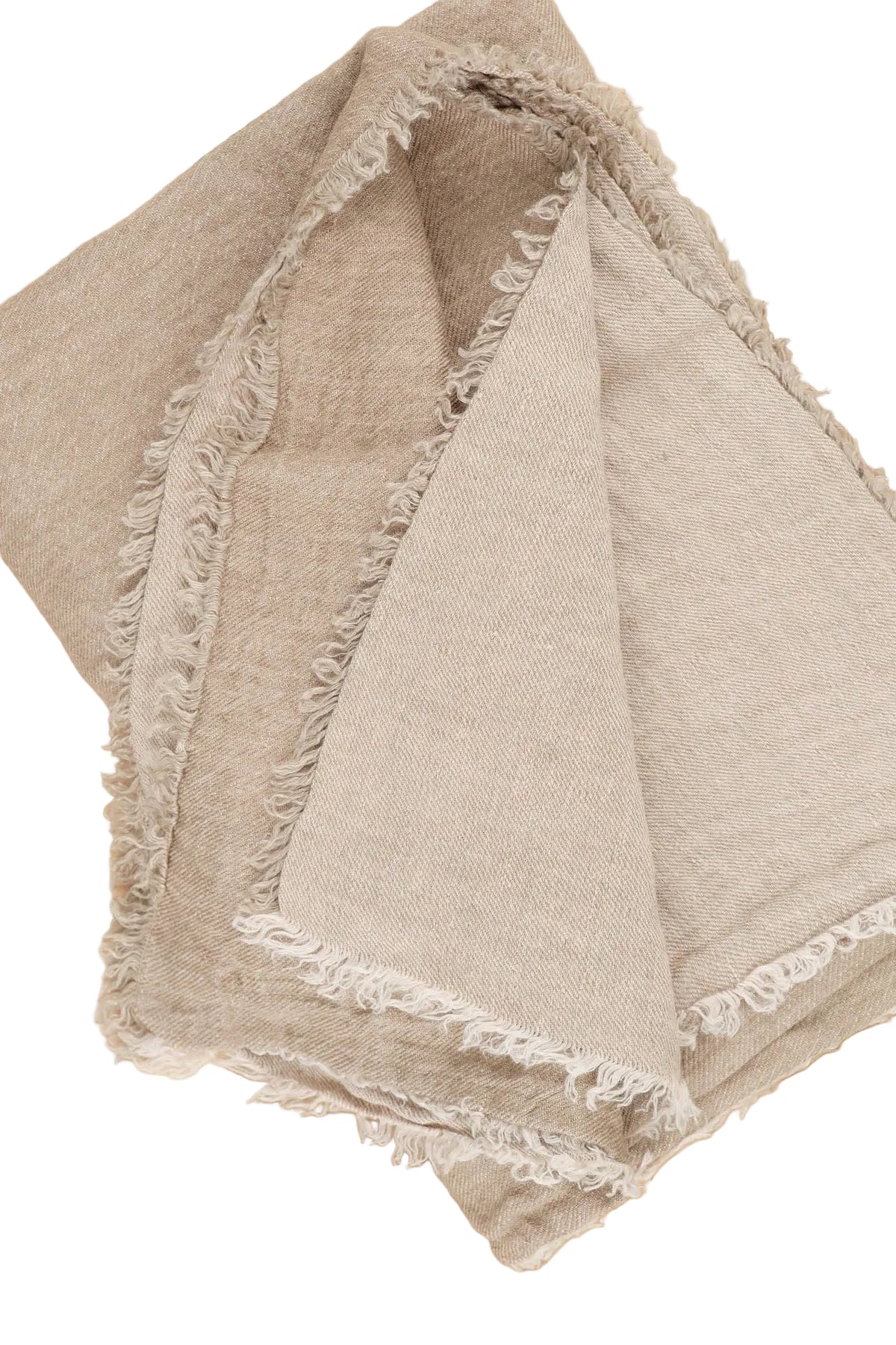 A folded beige linen throw blanket with frayed edges, displayed on a light wood surface.