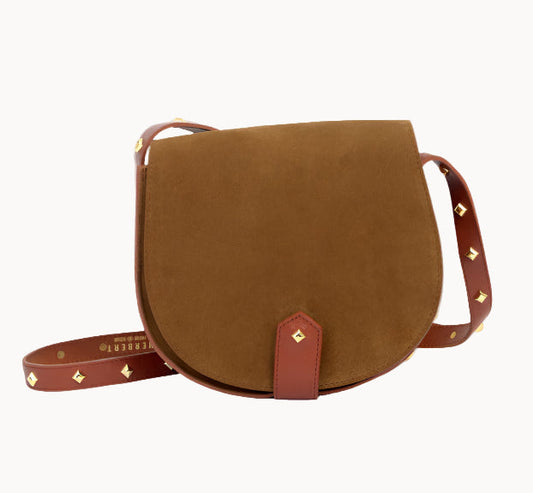 A tobacco brown suede handbag with brass studs on the strap and a flat zipped pocket on a white background